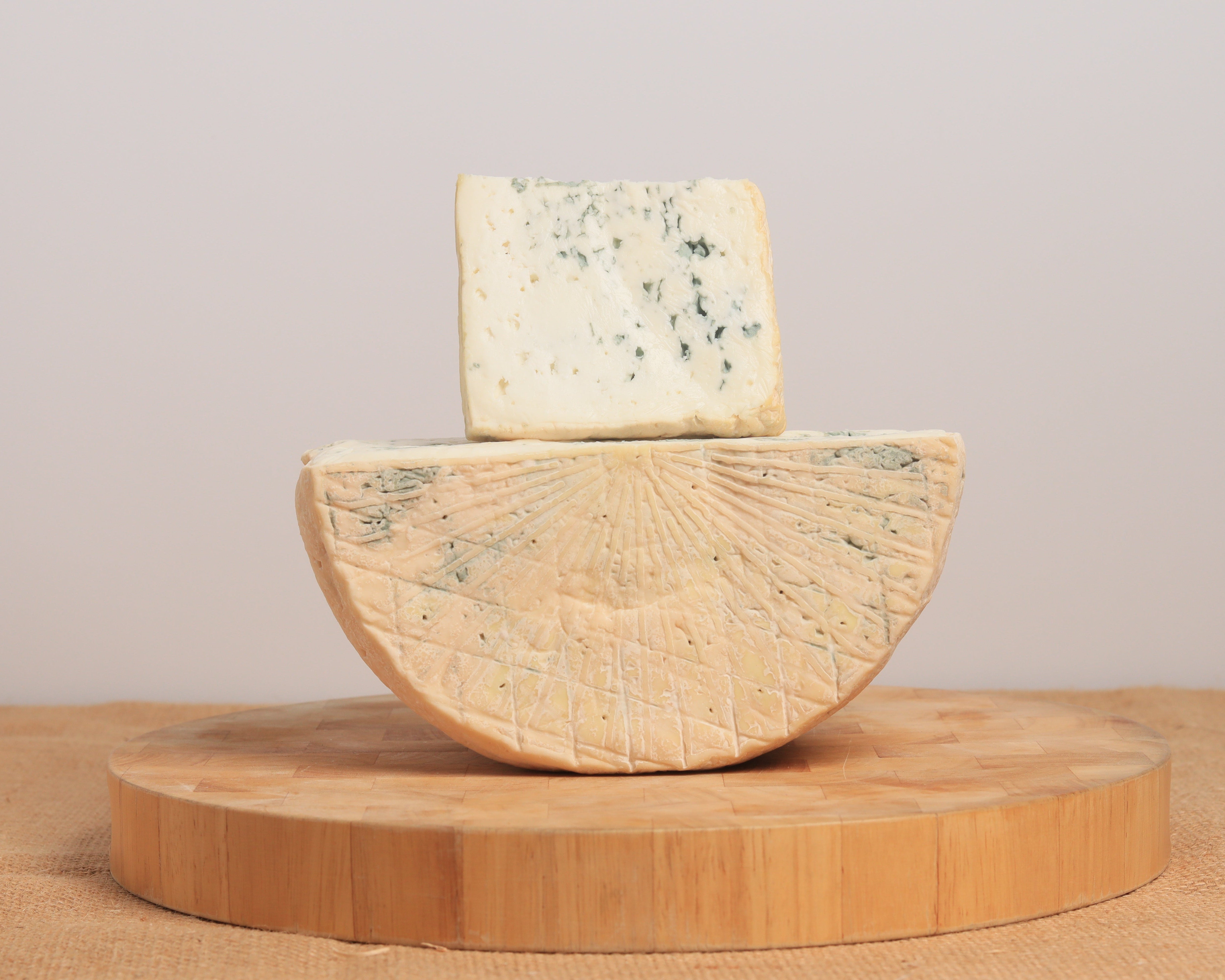 half a wheel of blue cheese with a wedge sitting on top