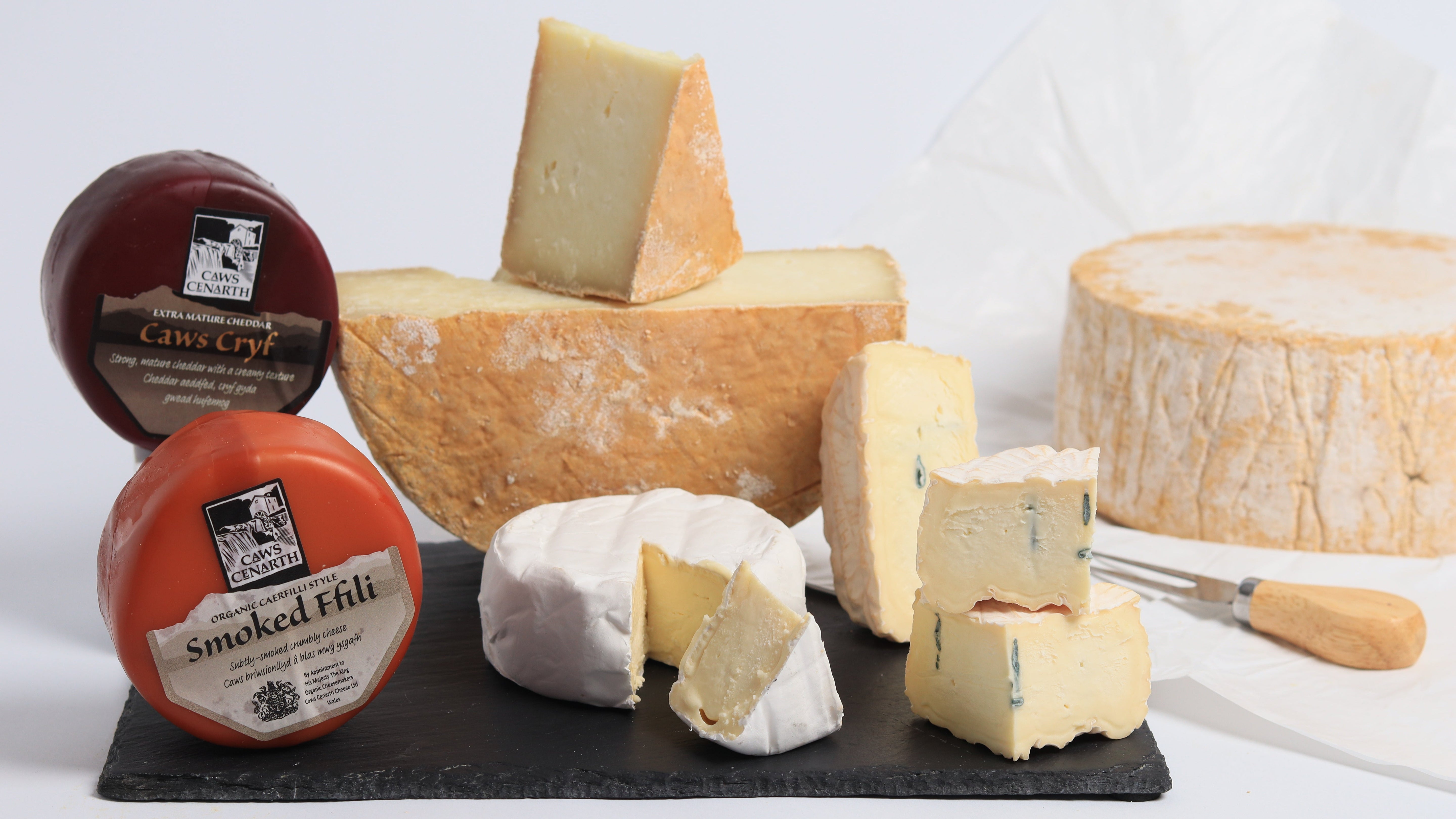 5 different cheeses on a slate with some unwrapped and cut open