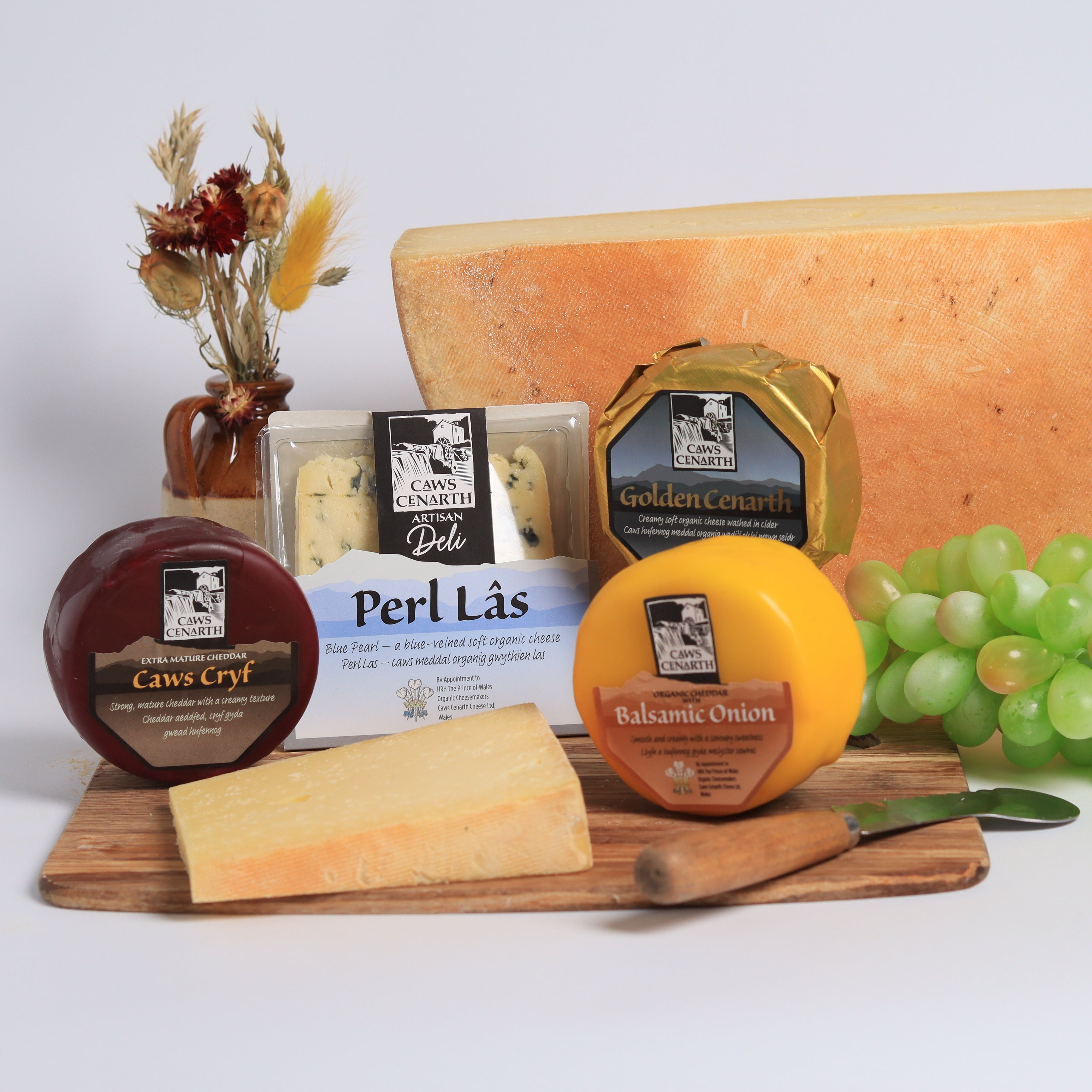 Assorted cheeses on a wooden board with grapes and a white background