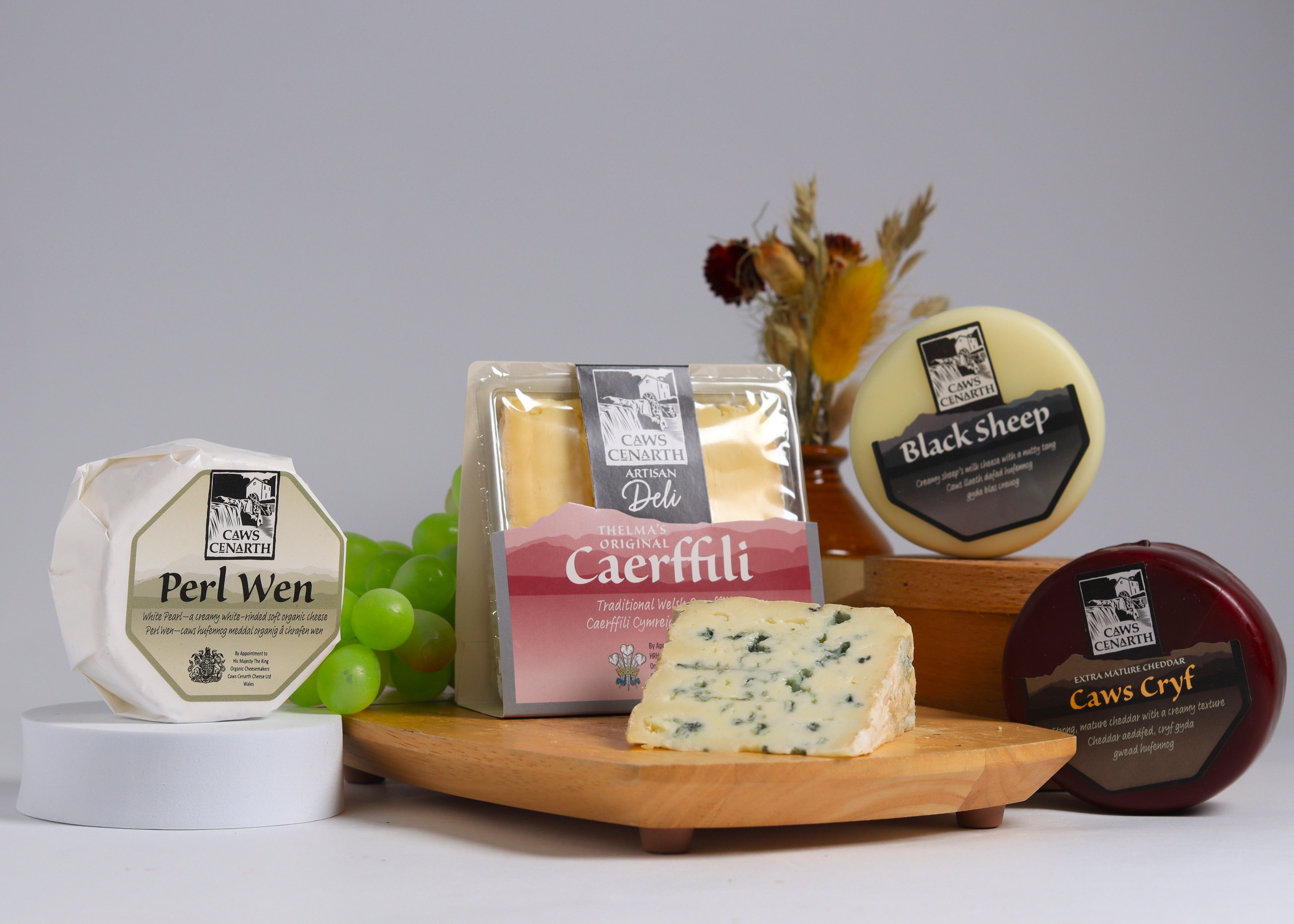 5 assorted Caws Cenarthcheeses on a wooden board with a grey background